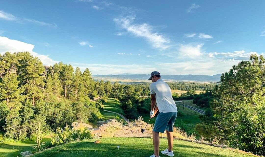 Golfer preparing a tee shot from an elevated fairway overlooking a valley