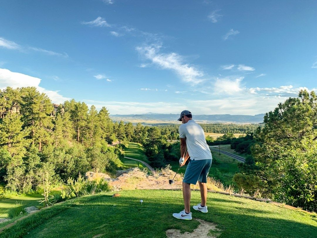 Golfer preparing a tee shot from an elevated fairway overlooking a valley