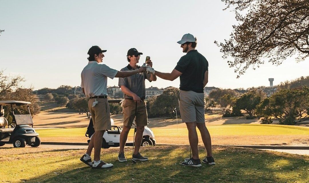 Three golfers clink drinks beside a golf cart on the course